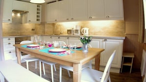 A modern kitchen with white cabinets, a wooden dining table set for four, and a coffee maker. - 250m from shops, 1st floor, balcony, ski locker, 55m², Valmorel (Valmorel)