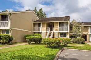 A two-story building with a central staircase, a covered front porch, and a parking lot. - Beach Cozy North Shore Turtle Bay Condo (Kahuku)
