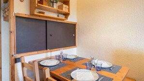Ein Essbereich mit einem Holztisch, gedeckt für vier Personen, einschließlich Teller, Besteck und Gläsern.