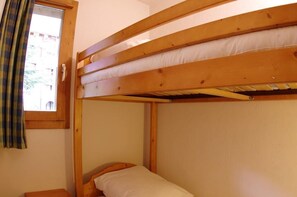 Un dormitorio con literas, ventana y cortinas.