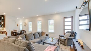 Una sala de estar amplia con un sofá modular, una mesa de centro y un televisor sobre un soporte de madera.