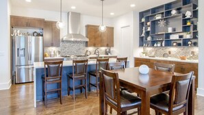 Una cocina moderna con una isla central, sillas de madera y estanterías empotradas.