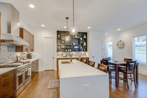 A modern kitchen with a central island, wooden cabinets, and a dining area with a large table and chairs.