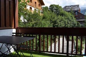 Enjoy outdoor dining or relaxation on this balcony overlooking a serene green area.