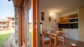 Una cucina accogliente con mobili in legno, un tavolo da pranzo e sedie. Si vede una finestra con vista sull'esterno.