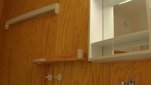 Un bagno con parete in legno, una vasca da bagno bianca, un lavandino bianco e uno specchio sopra il lavandino.