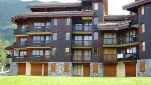 Un hotel a più piani con balconi, persiane in legno e facciata in pietra.