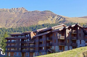 Un hôtel à plusieurs étages, doté de balcons, situé dans un cadre montagneux.