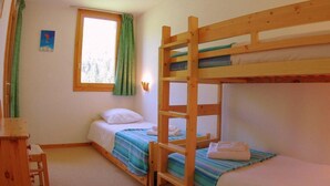 Una habitación con literas, un escritorio y una ventana con cortinas.
