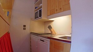 Una cocina funcional con lavavajillas, microondas y armarios de madera.