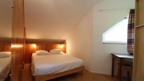 A bedroom with a wooden bed, a desk, and a window with curtains. - 100m from ski slopes, 3rd floor, balcony, tv, ski locker, 35m², Val Cenis (Lanslevillard)