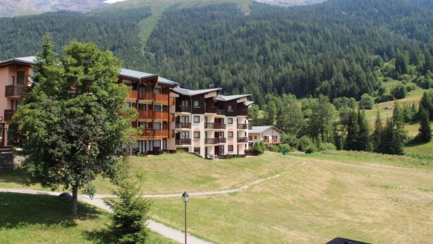 A multi-story hotel with balconies, set against a backdrop of forested mountains. - 100m from ski slopes, 3rd floor, balcony, tv, ski locker, 35m², Val Cenis (Lanslevillard)