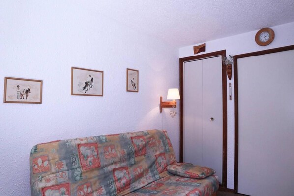 A room with a patterned sofa, a door, and three framed pictures on the wall.