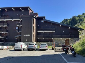 Un bâtiment sur lequel on peut lire l’inscription « Les Proveres », ainsi qu’un espace de stationnement où sont garées plusieurs voitures et une moto.