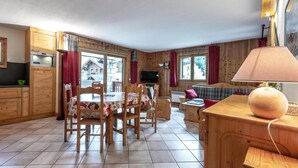 A cozy wooden interior with a dining area, a sofa, and a TV.