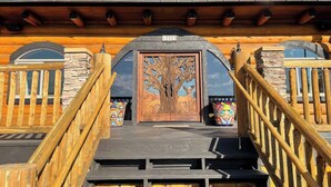 A wooden staircase leading to a door with a tree carving, flanked by stone walls and wooden railings.
