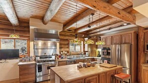 A spacious kitchen with wooden beams, stainless steel appliances, and a large island with stools.