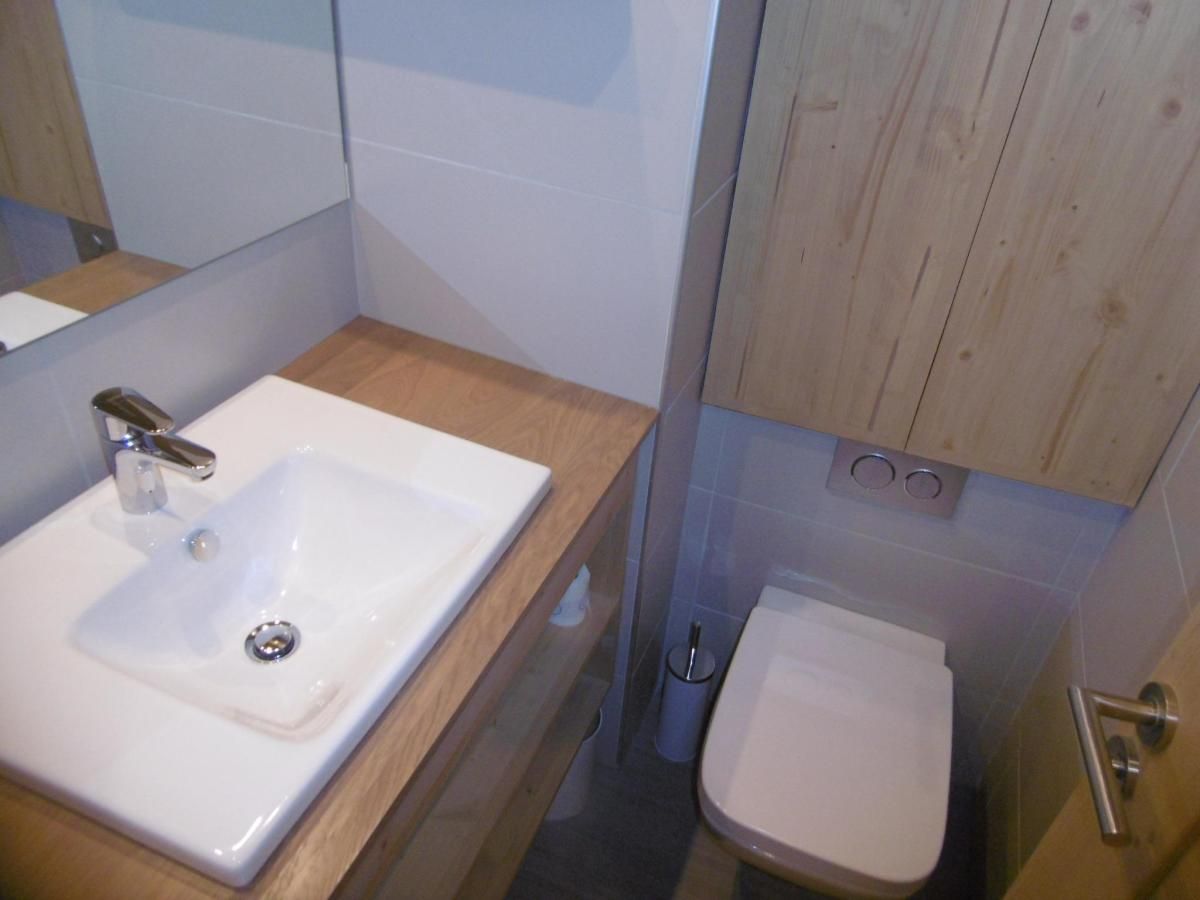 Een badkamer met een witte wastafel, toilet en een houten opbergmeubel.