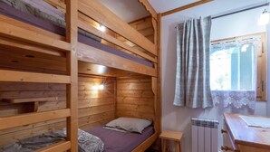 A wooden cabin with bunk beds, a small stool, and a radiator.