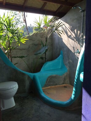 A bathroom with a hanging chair, a toilet, and a shower area. - Villa Pondok Apsari (Sukasada)