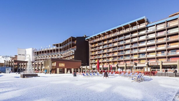 Un hotel con varios balcones, una fuente central y zonas de estar al aire libre.