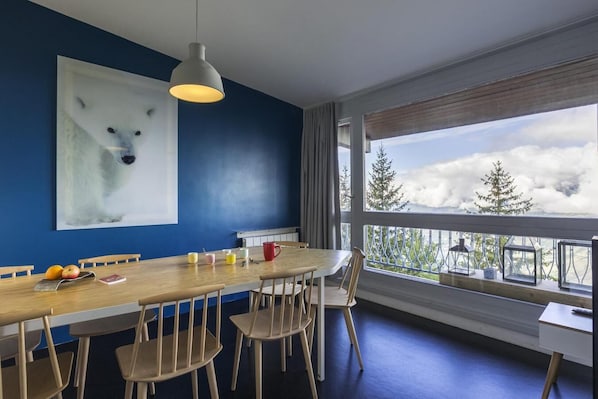Enjoy meals with a mountain view from this dining area featuring a long table for six and a large window.