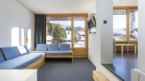 Une chambre moderne équipée d’un lit, d’un canapé et d’une grande fenêtre donnant sur un paysage enneigé.