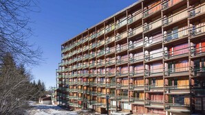 Un immeuble à plusieurs étages doté de nombreux balcons, chacun étant muni d’une rambarde et d’une fenêtre.