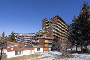 A multi-story hotel with balconies, a brick facade, and a snow-covered ground. - 100m from resort center, 15th floor, balcony, tv, 27m², Les Arcs (Les Arcs)