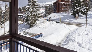 A snow-covered landscape with a wooden balcony and metal railing.