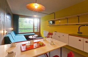 A modern kitchen with a dining area, a TV on the wall, and a view of the outdoors. - 100m from resort center, 10th floor, balcony, tv, 27m², Les Arcs (Les Arcs)