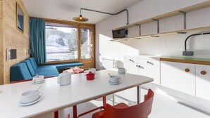 A modern kitchen with a white table, red chairs, and a blue bench. - 100m from resort center, 8th floor, balcony, tv, 27m², Les Arcs (Les Arcs)