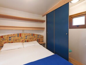 Un dormitorio con cama, armario y ventana.