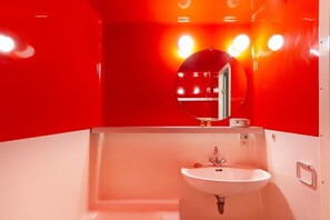 Ein Badezimmer mit einem weißen Waschbecken, einem Spiegel und roten Wänden.