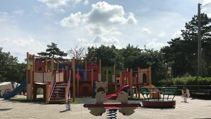 A playground with various play structures, including slides and climbing areas, under a tiled roof.