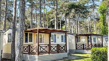 Eine Reihe von modularen Holzhäusern mit Holzgeländern, eingebettet in einen bewaldeten Bereich.