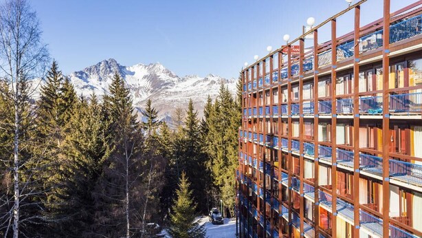 Un hotel de varios pisos con vistas a montañas nevadas.