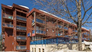 Un hotel de varios pisos con balcones y techo cubierto de nieve.