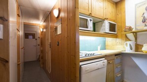 A narrow hallway leading to a kitchen with wooden cabinets, a microwave, a stove, and a sink. - 10m from ski slopes, 8th floor, terrace, tv, 27m², Les Arcs (Les Arcs)