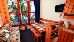 A cozy room with a wooden bench, a dining table set for two, and a television mounted on the wall.