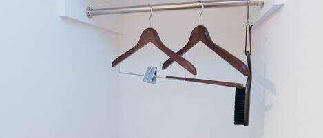 A clothing rack with two wooden hangers and a brush.