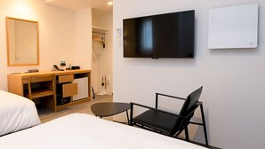 Une chambre d’hôtel comprenant un lit, un bureau avec une chaise, une télévision et une petite table.