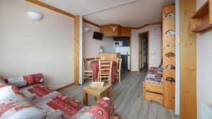 Una habitación acogedora con un sofá de madera, una mesita y una zona de cocina con microondas y televisión.