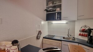 A kitchen with white cabinets, a stainless steel sink, and a coffee maker. - 10m from ski slopes, view ski slopes, balcony, tv, 26m², La Plagne (Aime)