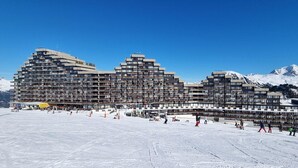 A large, multi-story hotel with a unique architectural design, situated in a snowy mountainous area. - 10m from ski slopes, view ski slopes, balcony, tv, 26m², La Plagne (Aime)