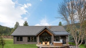 Une maison moderne dotée d’un grand patio, d’un espace salon extérieur et d’une cheminée.