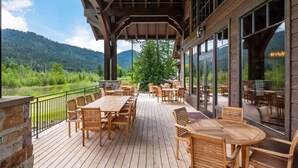 Une terrasse en bois avec des sièges extérieurs, offrant une vue sur un lac et des montagnes.