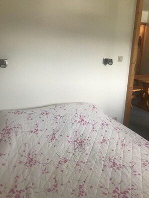 A bed with a quilted cover featuring a floral pattern.
