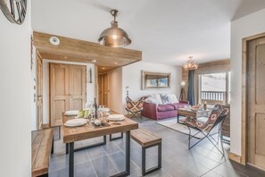 Una sala de estar acogedora con techo de madera, una zona de comedor con mesa de madera y un sofá rojo.