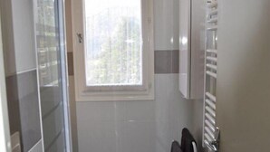 Ein Badezimmer mit Fenster, Handtuchhalter und einem weißen Schrank.